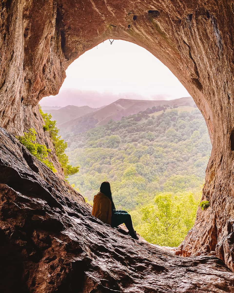 Girl sitting in Thor's Cave Entrance Peak District